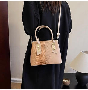 Detail of light brown tote bag with crocodile texture and gold hardware on model