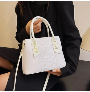 Detail of white crocodile embossed tote with gold chain accents and sturdy double handles