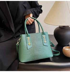 Close-up of green crocodile texture handbag with gold chain detail and top handle