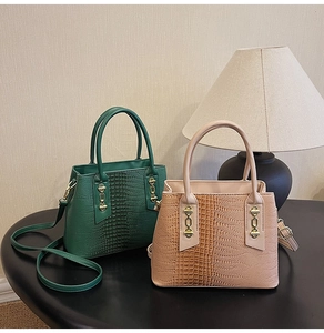 Detailed view of crocodile pattern leather handbags in dark green and beige with gold chains