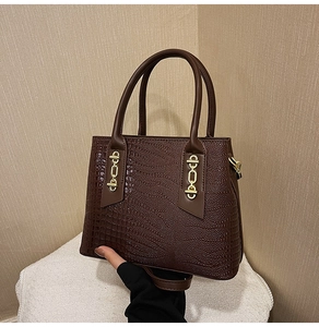 Detail of dark coffee crocodile pattern handbag with elegant gold metal chain buckle