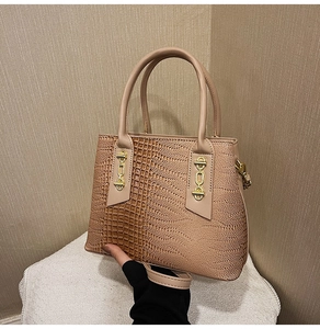 Detail of beige tote bag with crocodile texture, gold hardware and adjustable strap