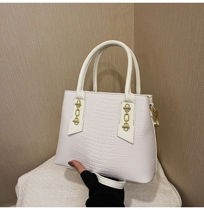 Close-up of white crocodile pattern PU leather texture and gold metal buckle details