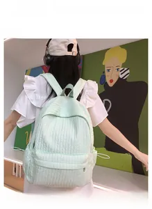 Détail d'un sac à dos vert menthe à texture plissée et poches latérales sur mannequin