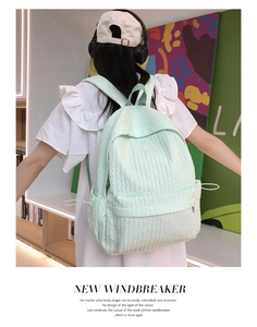 Détail de la texture gaufrée d'un sac à dos vert menthe porté par une étudiante