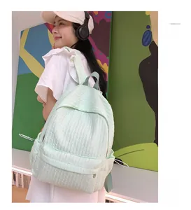Gros plan d'un sac à dos vert menthe avec tissu à texture plissée et poche latérale