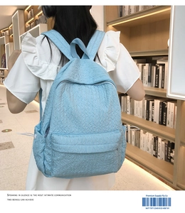 Détail d'un sac à dos bleu clair avec texture ondulée et poche à cordon dans une bibliothèque