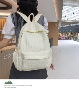 Détail d'un sac à dos blanc crème en tissu texturé seersucker porté par un modèle
