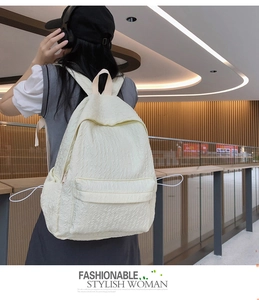 Détail du sac à dos crème avec texture plissée unique et grande poche frontale