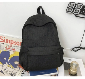 Détail du tissu noir froissé et de la poche à fermeture éclair cachée sur le sac à dos