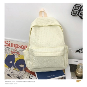 Détail d'un sac à dos blanc crème avec texture plissée et design à poches multiples