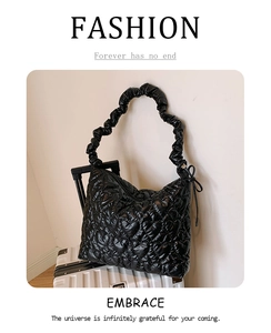 Detail of black quilted heart patterns and scrunchie strap on padded shoulder bag