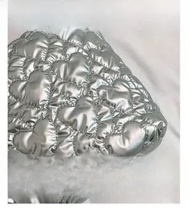 Detailed close-up of silver heart-shaped quilted metallic fabric with high-gloss finish