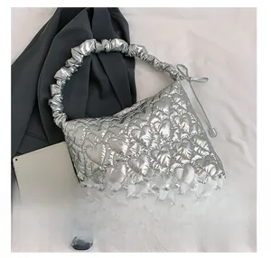 Detail of silver heart-quilted tote bag featuring ruffled handles and bow accents
