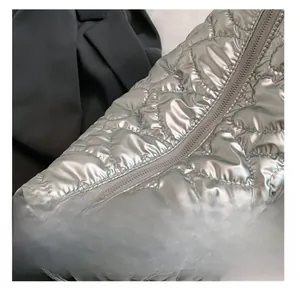 Detail of silver heart-quilted fabric with smooth metal zipper closure on the handbag