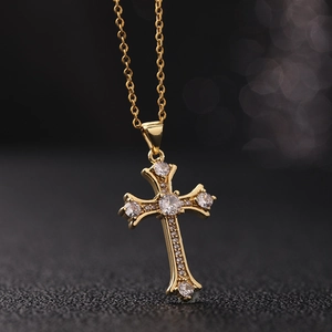 Dettaglio della collana con croce placcata oro e zirconi bianchi su sfondo scuro