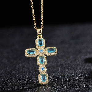 Collier croix dorée avec pierres de zircon bleues et accents de diamants sur fond noir