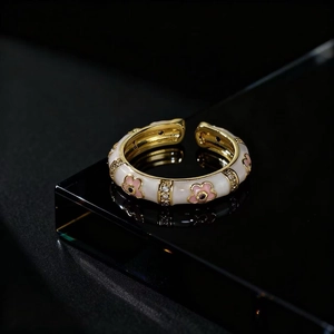 Macro detail of gold vintage flower ring with white enamel and sparkling zircon accents