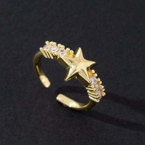 Détail macro de la bague étoile dorée avec zircons étincelants sur fond noir