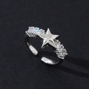 Gros plan détaillé d'une bague étoile en argent avec zircons sur un fond sombre texturé