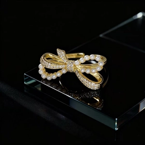 Macro detail of golden bow ring with white pearls and sparkling pavé crystals