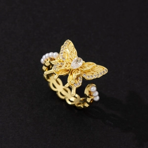 Macro shot of golden butterfly ring featuring zircon pavé wings and pearl chain band