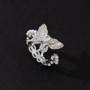 Macro detail of silver butterfly ring featuring sparkling diamonds and elegant white pearls