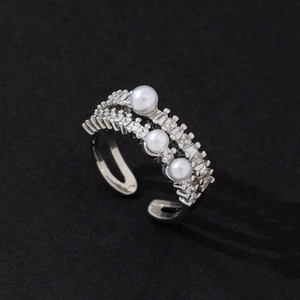 Detail of elegant silver ring featuring three pearls and sparkling cubic zirconia