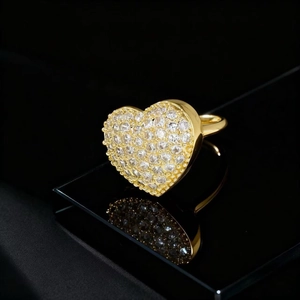 Detailed view of a gold heart-shaped ring with pavé-set crystals on a black reflective base