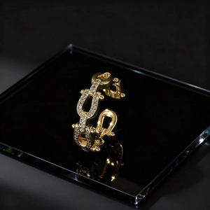 Gold U-shaped horseshoe link ring with pavé micro-set zircon on black reflective surface