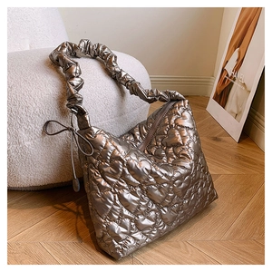 Detailed close-up of heart-shaped quilted stitching on a golden puffer shoulder bag
