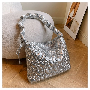 Detail of silver heart-quilted texture and stylish ruched handle on the tote bag