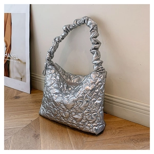 Close-up of silver quilted handbag with heart stitching and ruched elastic handle