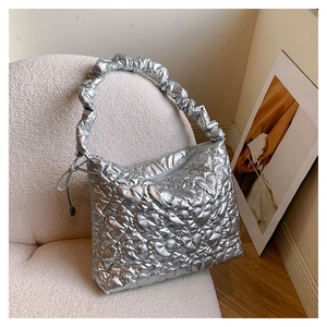 Detail of silver metallic puffy bag featuring heart-shaped quilting and ruched shoulder strap