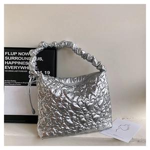 Close-up of silver quilted heart handbag with trendy ruched cloud-style handle design