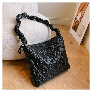 Detailed view of heart quilted pattern on black glossy nylon shoulder bag with ruched strap