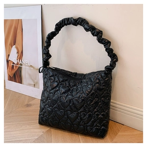 Detail of heart-quilted texture and ruched handle on a black fashionable shoulder bag