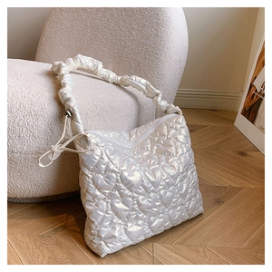 Close-up of white heart-quilted shoulder bag with ruched strap and pearl luster finish