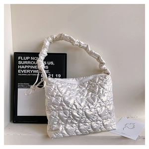Detailed view of heart-shaped quilting and ruched handle on cream shoulder bag