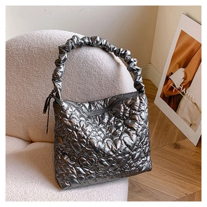 Detailed silver quilted tote bag with heart patterns on a soft beige fleece armchair