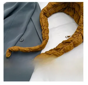 Macro shot of brown quilted puffy strap with glossy nylon fabric and gold metal zipper