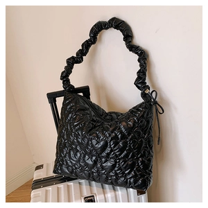 Detail of black glossy nylon shoulder bag with heart quilting and pleated handles