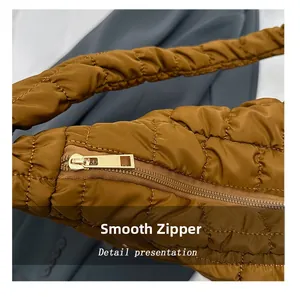 Macro view of smooth golden metal zipper on brown quilted nylon cloud crossbody bag