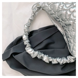 Detail of silver metallic quilted shoulder bag with heart pattern and ruched strap