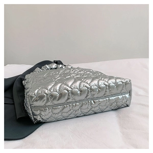 Detail of silver heart-quilted tote bag with glossy metallic finish and pleated handle