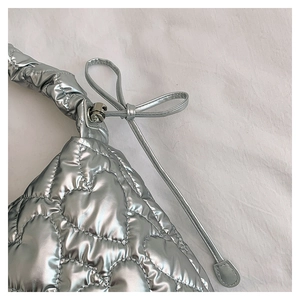 Detail of silver quilted handbag featuring heart stitching and ruffled strap bow