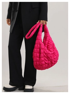 Detail shot of bright pink quilted cloud bag with padded texture and wide shoulder strap