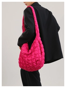Close-up of rose pink quilted puffer bag showing large capacity and textured fabric on model