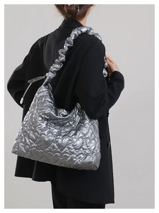 Macro view of silver metallic heart quilted tote bag with ruffled shoulder strap detail