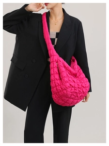Close-up of vibrant pink quilted cloud bag with textured bubble pattern on a model